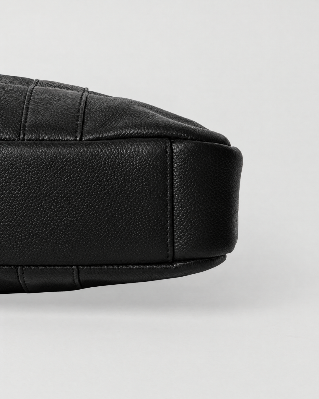 Base detail of the Laylowe Nolan black leather laptop case showing its slim profile and stitched leather panels.