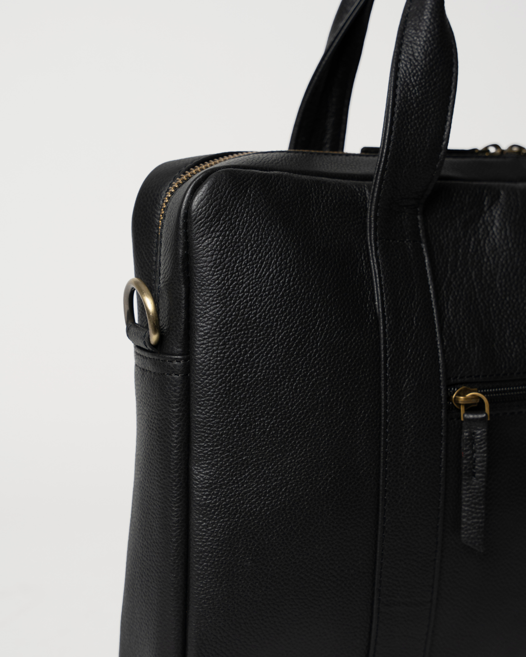 Laylowe Nolan black leather laptop case detail showing the shoulder-strap ring, top zipper and pebbled leather.