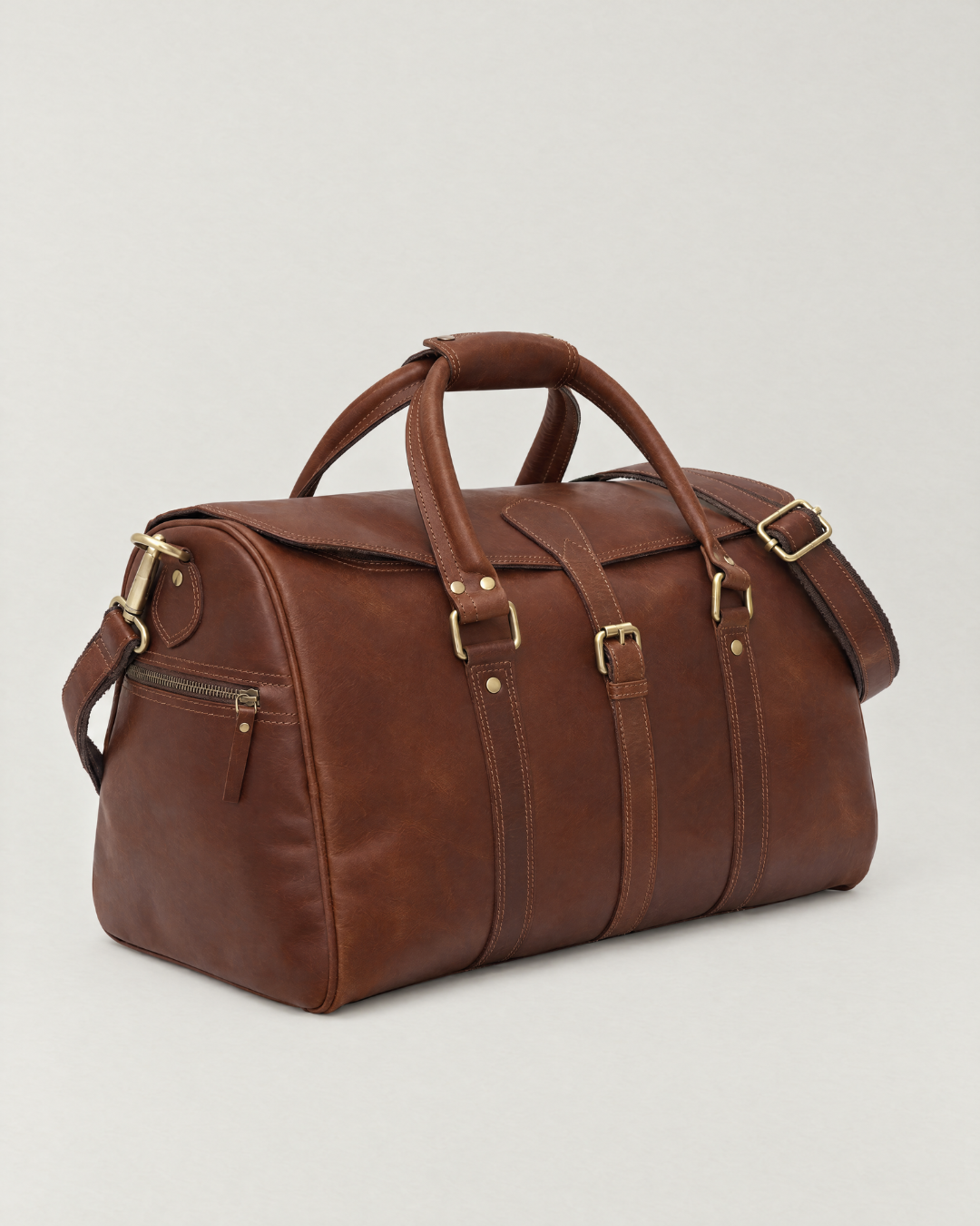 Laylowe Parker tan full-grain leather weekender with rolled handles, a buckled flap and shoulder strap.
