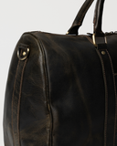 Laylowe Beck dark brown small leather duffle detail showing its rounded end, shoulder strap ring and stitched trim.
