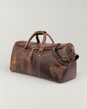 Angled view of the Laylowe Rhodes light brown leather duffle showing an end zip pocket, carry handles and shoulder strap.