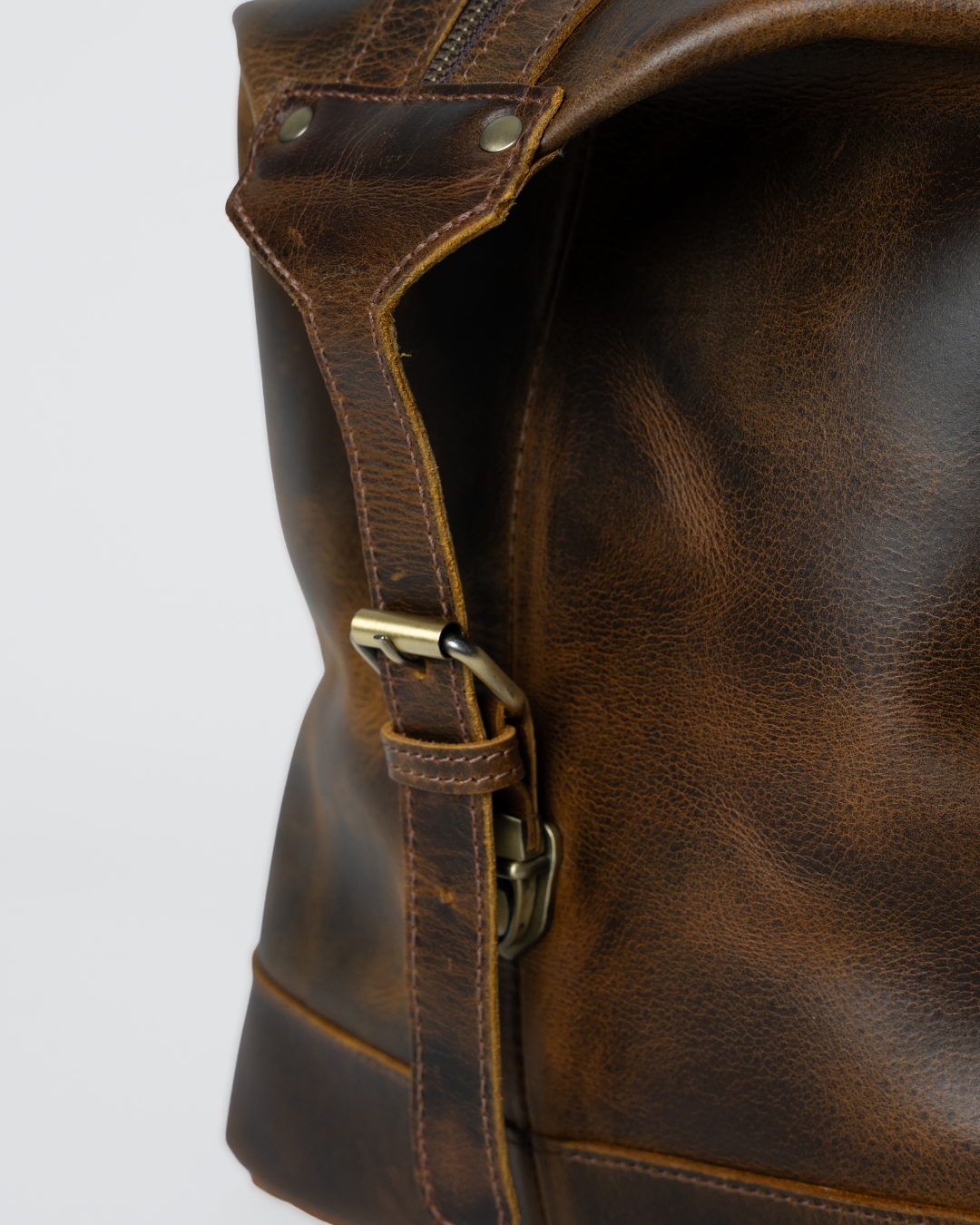 Close-up of the Laylowe Hayes light brown leather weekender showing the adjustable side buckle and leather grain.