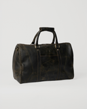 Laylowe Beck dark brown small leather duffle, angled view showing the rounded end and front slip pocket.