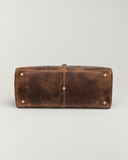 Bottom view of the Laylowe Rhodes light brown leather travel bag showing five metal feet and stitched edges.