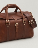 Close-up of the Laylowe Parker tan leather weekender showing the front buckle, handle wrap and strap hardware.