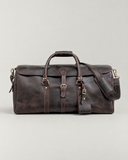 Front view of the Laylowe Rhodes large dark brown leather travel bag with a buckled flap, carry handles and shoulder strap.