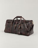 Side angle of the Laylowe Rhodes dark brown leather duffle showing an end zip pocket and padded shoulder strap.
