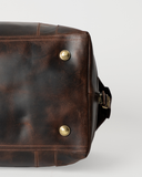 Base detail of the Laylowe Hayes dark brown leather weekender, showing metal feet and brown stitching.