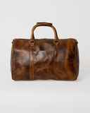 Front view of the Laylowe Beck small leather duffle in light brown with a slip pocket and wrapped carry handles.
