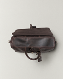 Top view of the Laylowe Rhodes dark brown leather travel bag with its outer flap folded back and inner zipper closed.