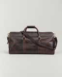 Rear view of the Laylowe Rhodes dark brown leather travel bag with its shoulder strap across the leather panels.