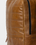 Close-up of the Laylowe Lane tan leather backpack showing the main zipper, leather grain and horizontal stitching.