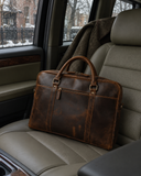 Laylowe Reid dark brown leather briefcase resting on a light gray car seat with a coat behind it.