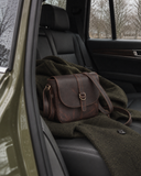 Laylowe Cora dark brown leather satchel resting on an olive coat on a black car seat.