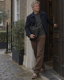 Man stepping through a doorway carrying the Laylowe Nolan black leather laptop case under his arm.