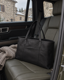 Laylowe Arden black leather tote bag on a car passenger seat beside a folded knit.