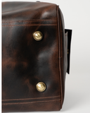 Laylowe Holden dark brown leather travel bag base detail showing metal feet and stitched leather edges.