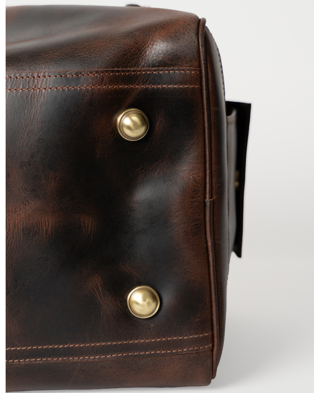Laylowe Holden dark brown leather travel bag base detail showing metal feet and stitched leather edges.