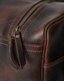 Laylowe Bennett dark brown leather travel bag detail showing a zipper with leather pull, piping and stitching.
