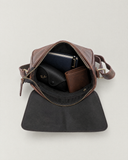 Laylowe Cora dark brown leather satchel open with a journal, pen, glasses case and wallet inside.