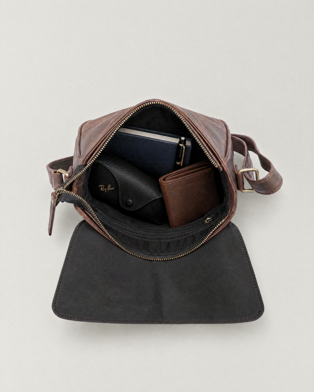 Laylowe Cora dark brown leather satchel open with a journal, pen, glasses case and wallet inside.