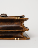 Close-up of the Laylowe Grant brown leather briefcase showing its accordion-style side panels and stitched edges.