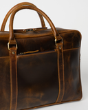 Close-up of the Laylowe Reid brown leather briefcase showing rolled handles, zip openings and mottled leather grain.