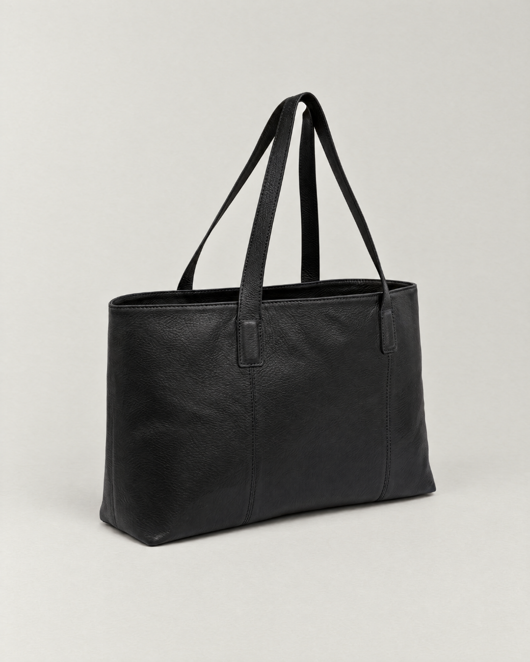 Laylowe Arden black leather tote bag, angled view showing long shoulder handles and a rectangular silhouette.