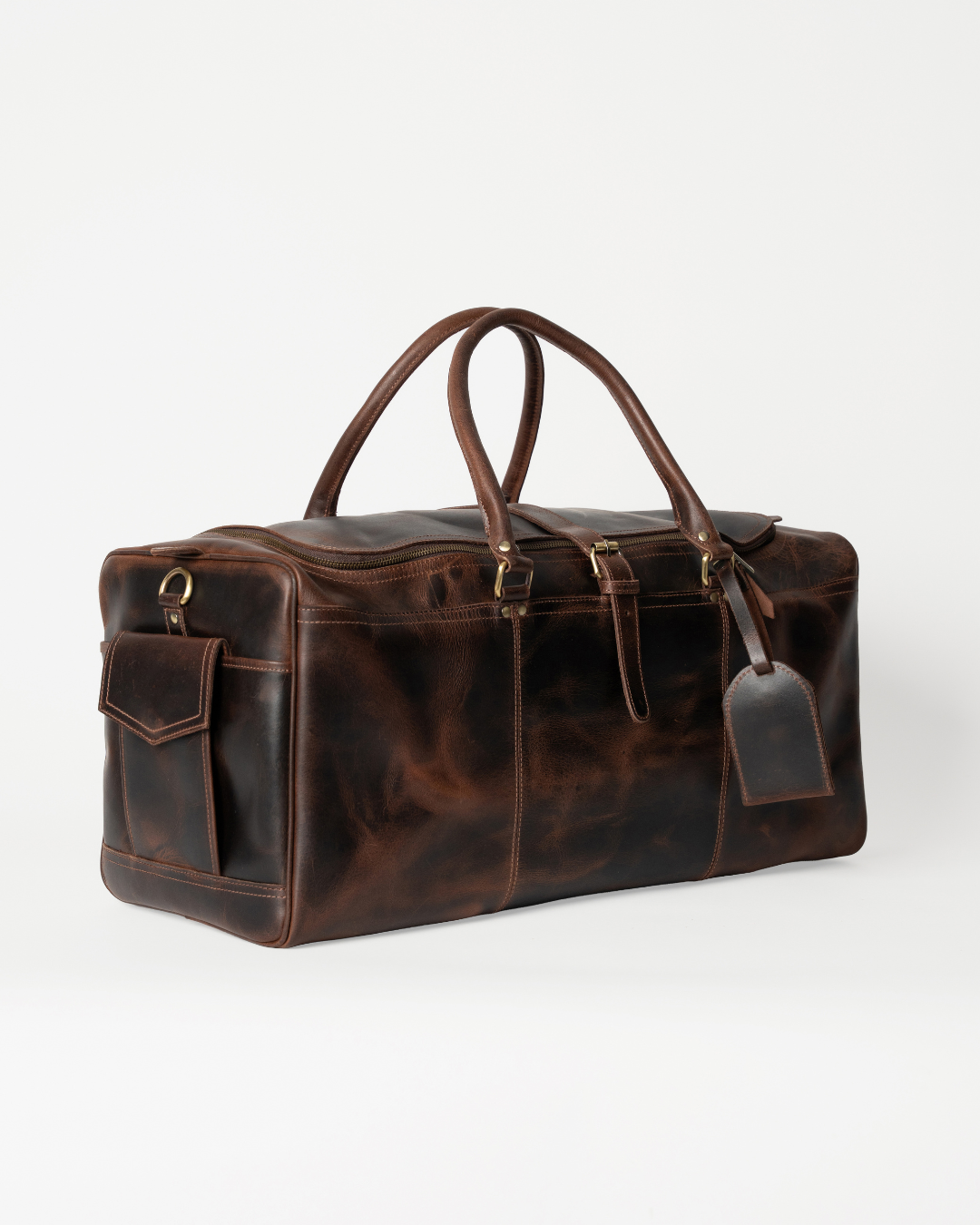 Laylowe Holden dark brown full-grain leather travel bag, angled view with carry handles, end flap pocket and luggage tag.